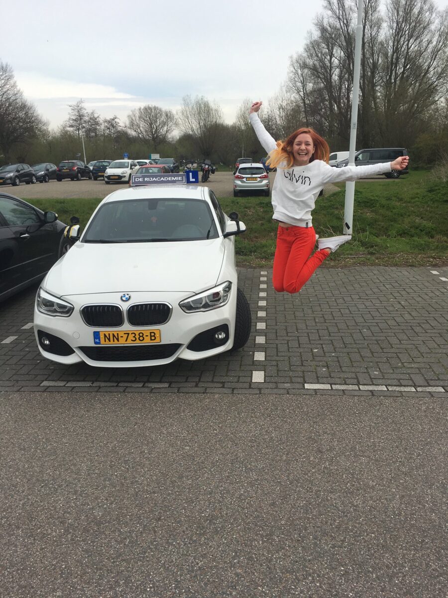 Yana springt van blijdschap naast de lesauto